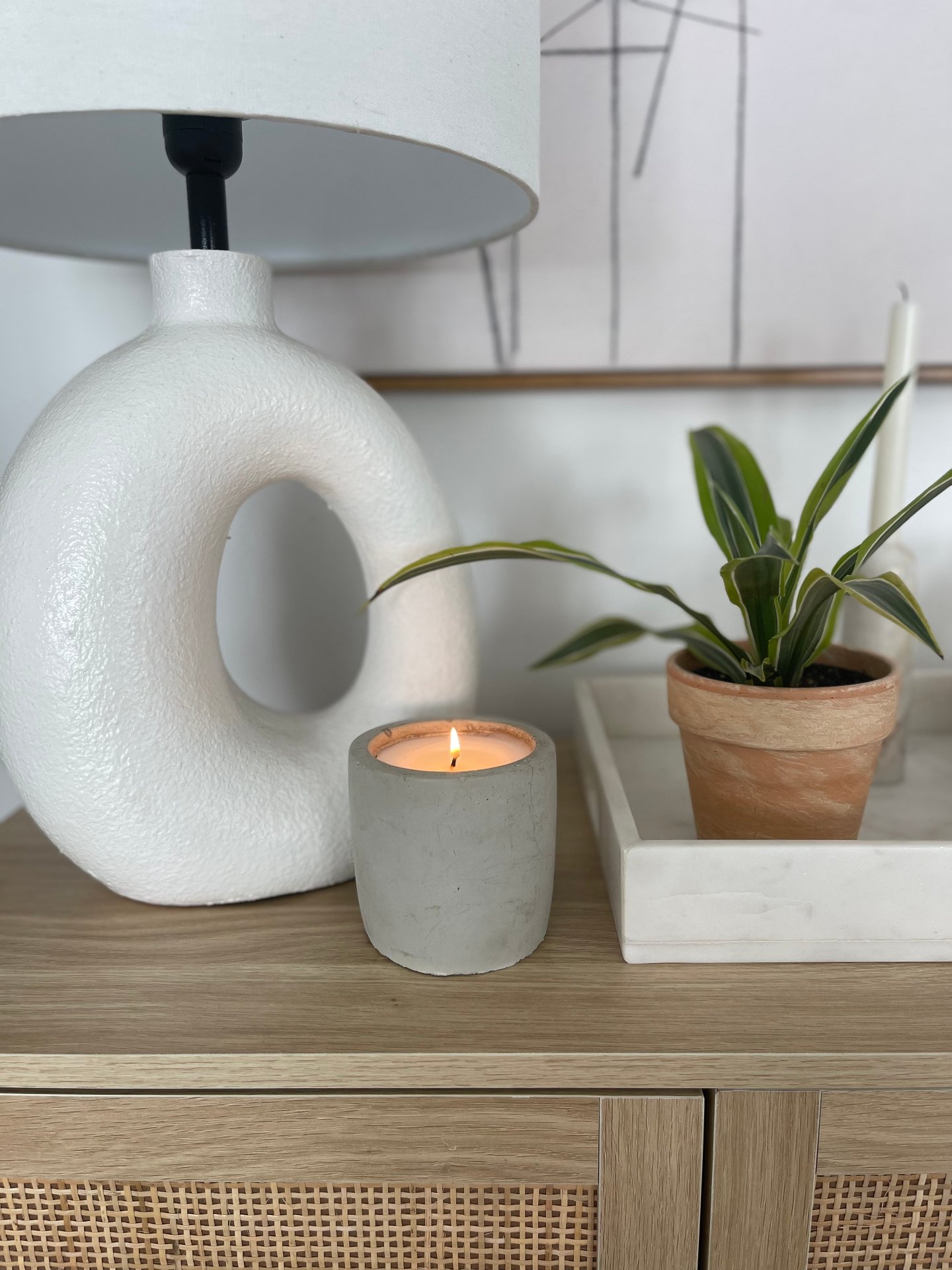 a lit candle on a dresser, low evening light, wick trimmed short