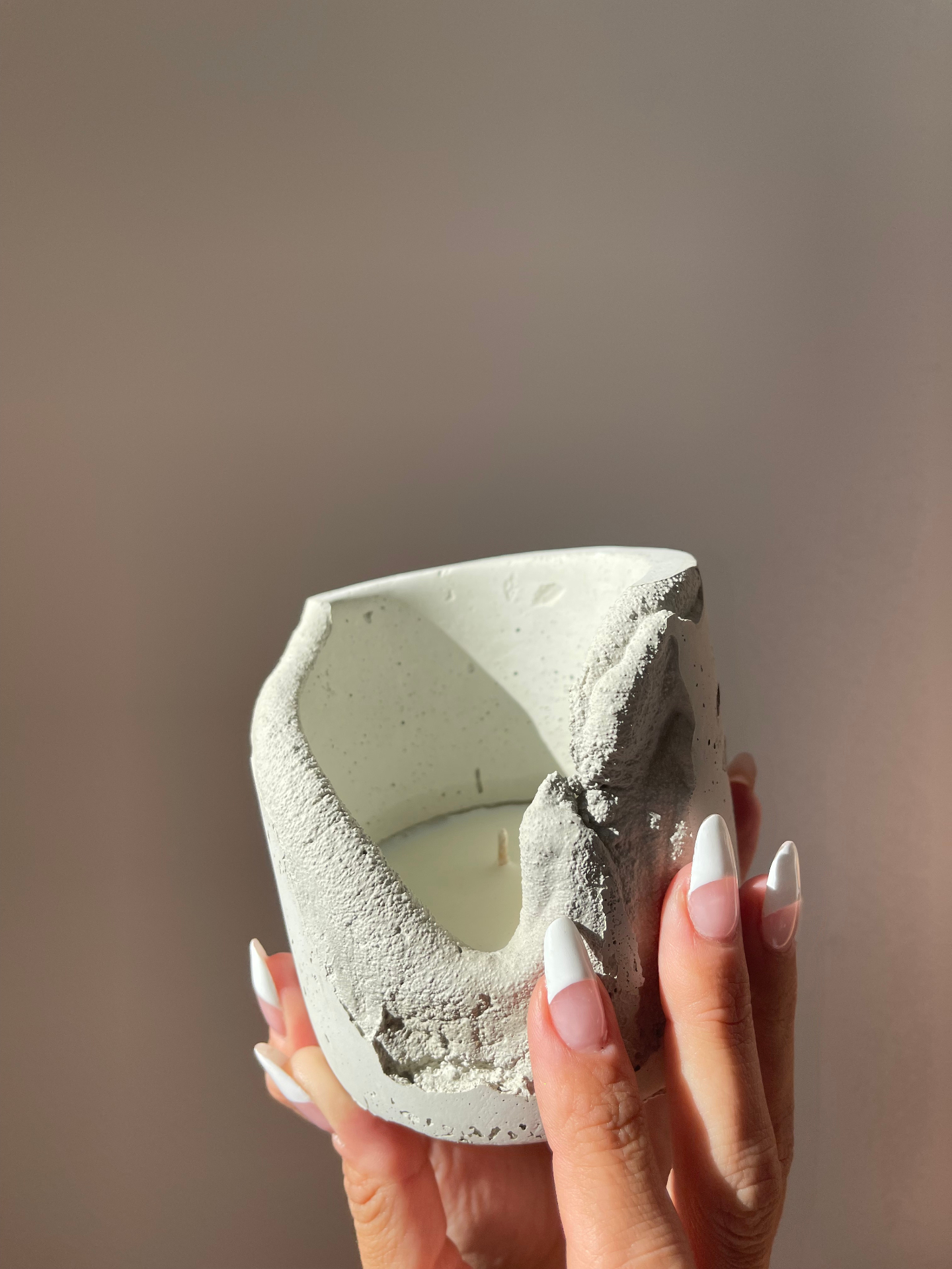 hands cradling a concrete coconut-wax candle vessel
